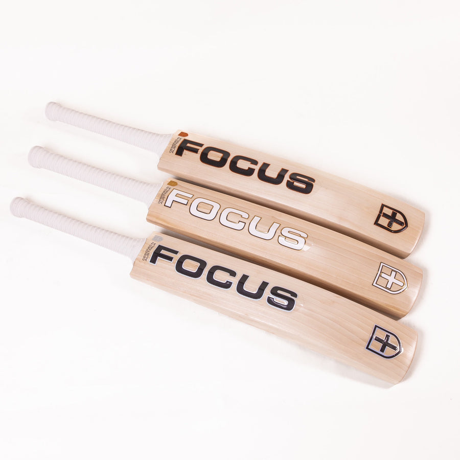 A premium-grade cricket bat from Focus, displayed from three different angles – front, back, and side view. The bat features a light-colored willow blade with a sleek design, bold focus cricket branding